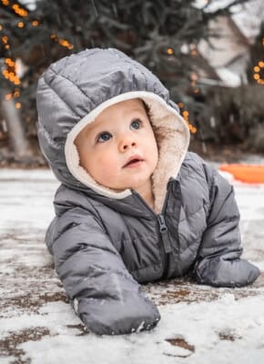 Niemowlę siedzące na śniegu w zimowej kurtce